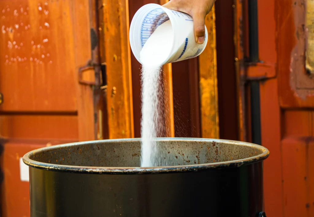 Pouring WUNDERSAND rapid concrete slurry solidifier powder into a bucket before treating concrete slurry waste.